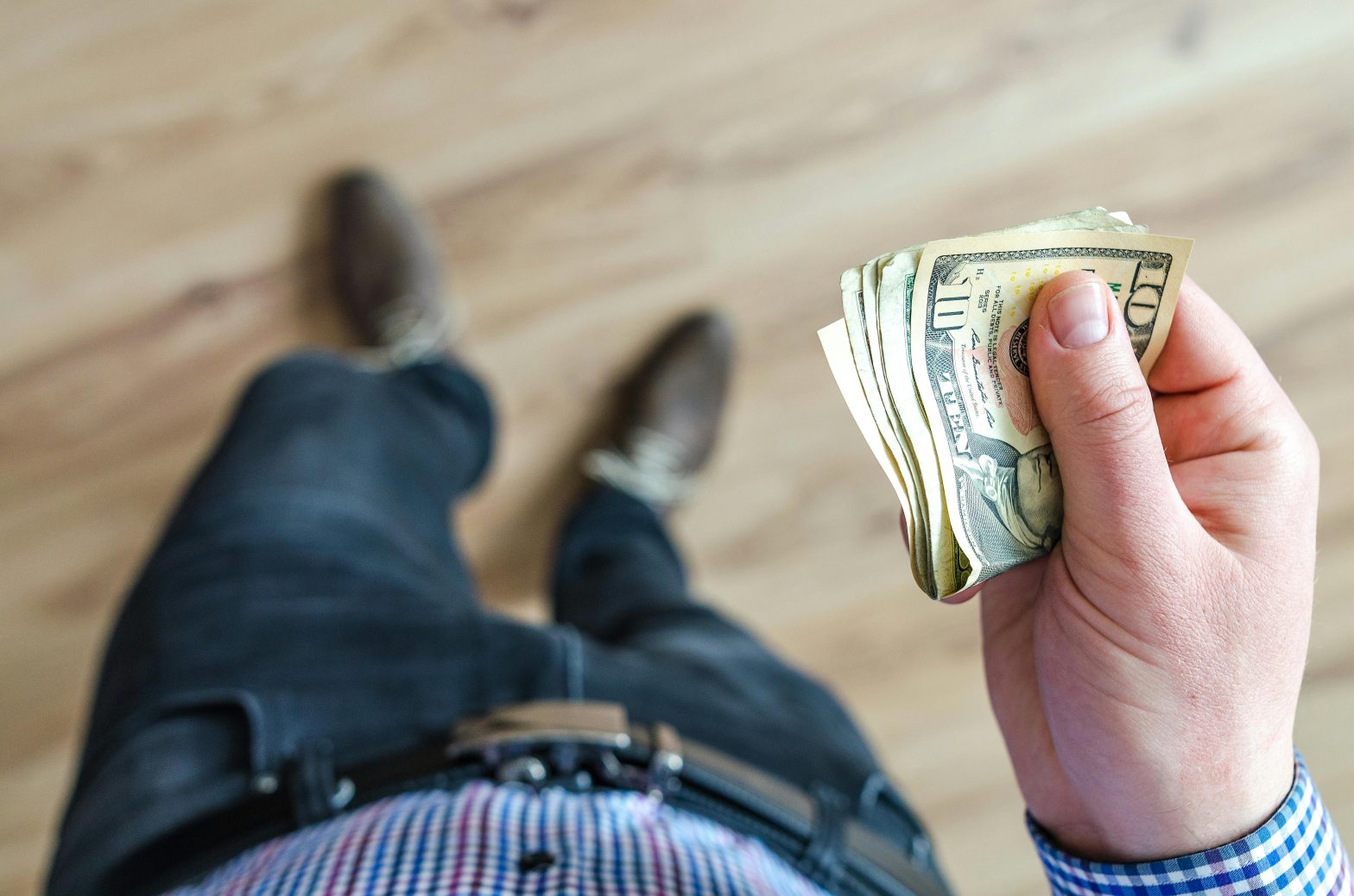 Man holds a 10 U.S. dollar bill, close-up of hand with a focus on the currency note.