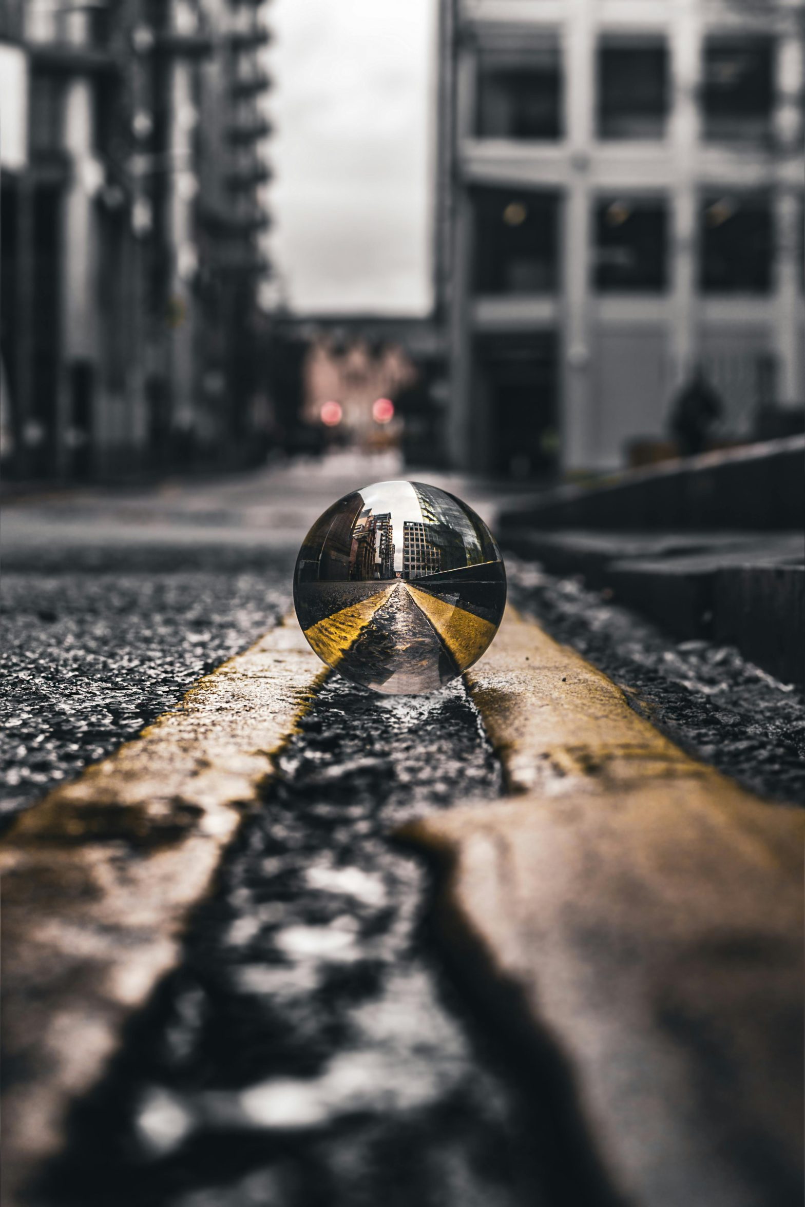 A lensball on an asphalt road, reflecting an inverted view of a cityscape.