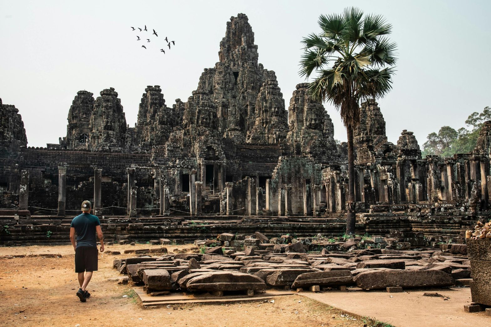 Scenic view of ancient temple ruins surrounded by lush greenery in Cambodia.